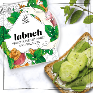 AlDar Mazza Labneh Brotaufstich neben einer Scheibe Brot. Labneh ist ein Aufstrich aus Quark mit Minze, Walnuss und Knoblauch.